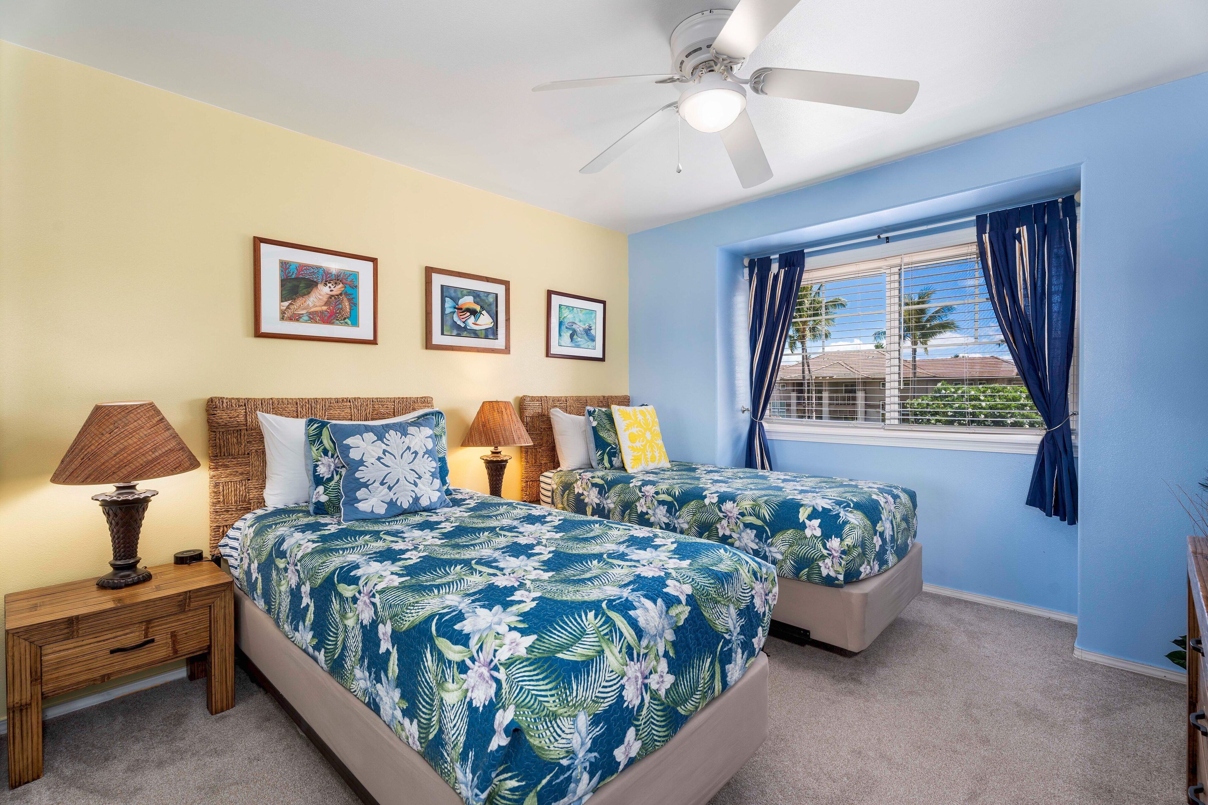 A bedroom with two beds, a ceiling fan, and a window with curtains.