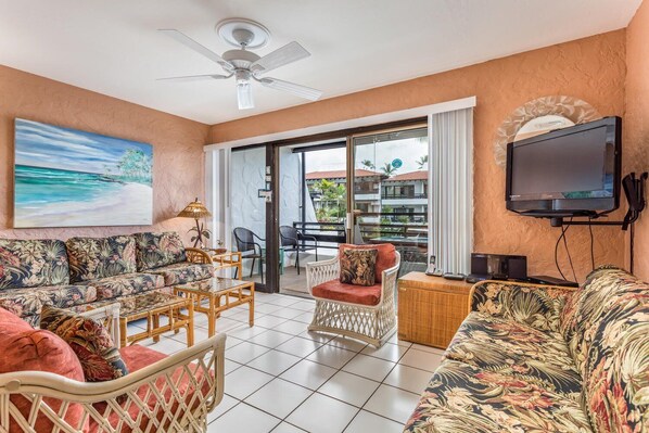 A living room with a sofa, chairs, a TV, and a ceiling fan.