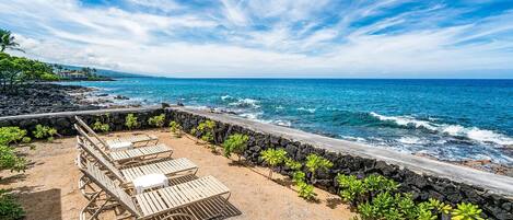 A beachside patio with lounge chairs and a view of the ocean.