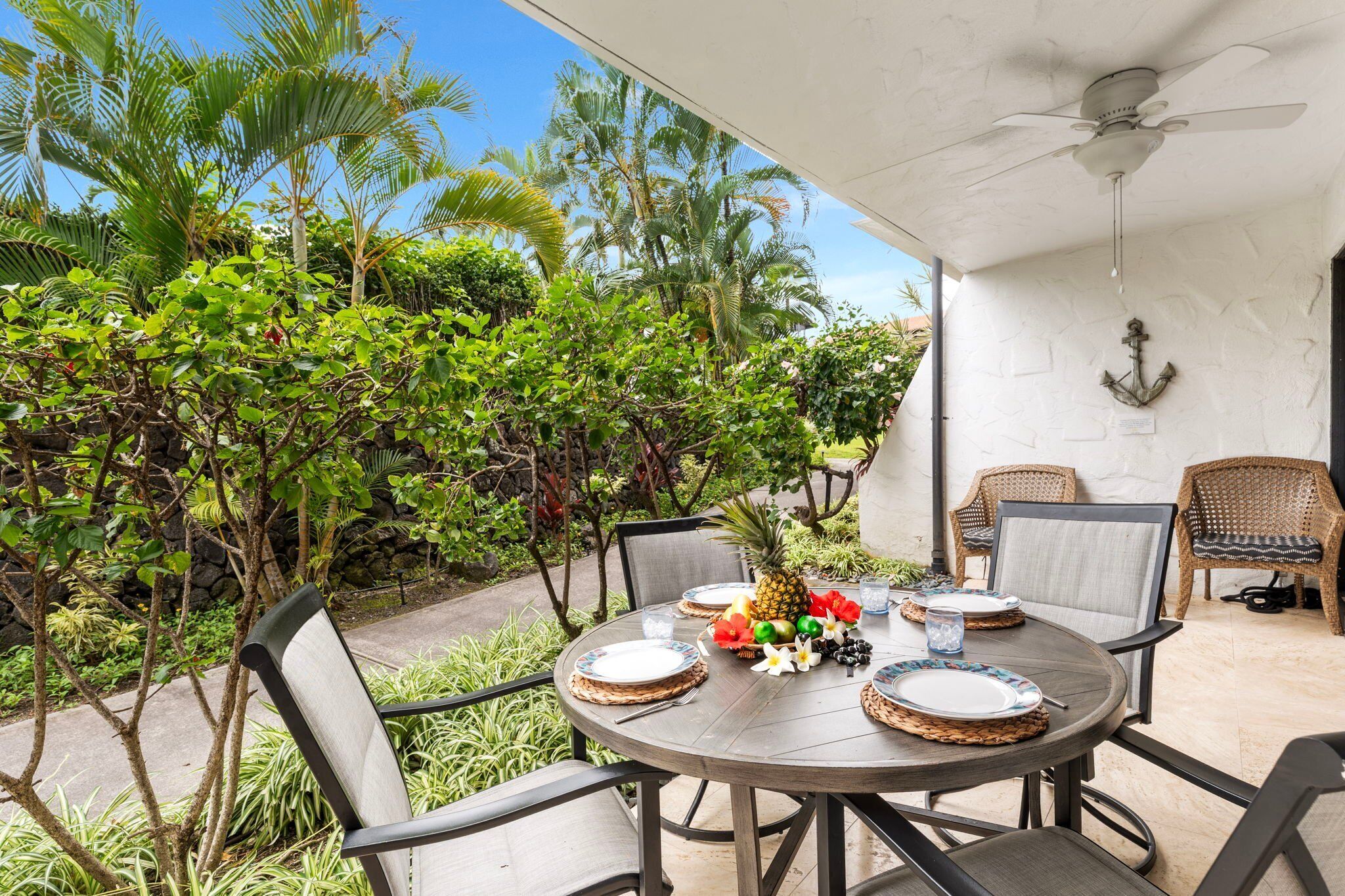 An outdoor dining area with a round table, chairs, and a ceiling fan.