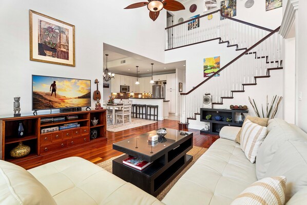 Amplia sala de estar con un sofá blanco grande, un mueble de entretenimiento de madera y un comedor.