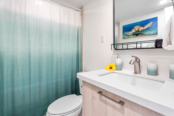 A bathroom with a shower curtain, toilet, sink with a mirror, and a towel rack.