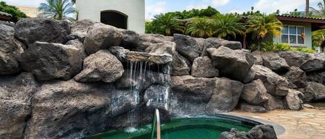 Une piscine agrémentée d’une cascade et entourée de gros rochers.