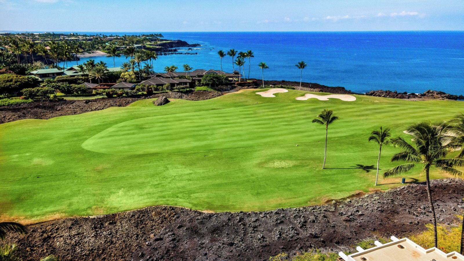 A golf course with a view of the ocean and a small building in the background.