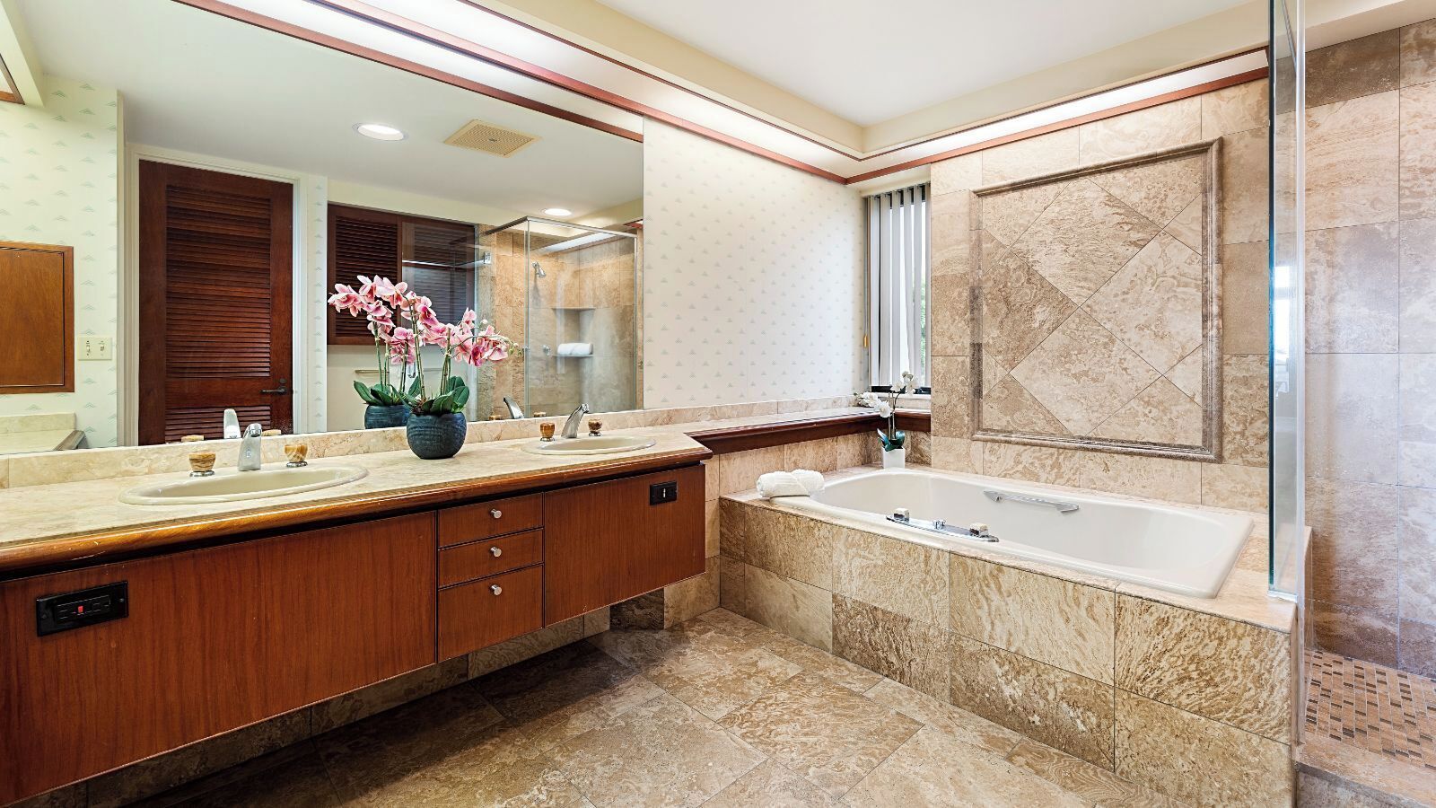 A modern bathroom with a large mirror, a double sink vanity, a bathtub, and a shower area.