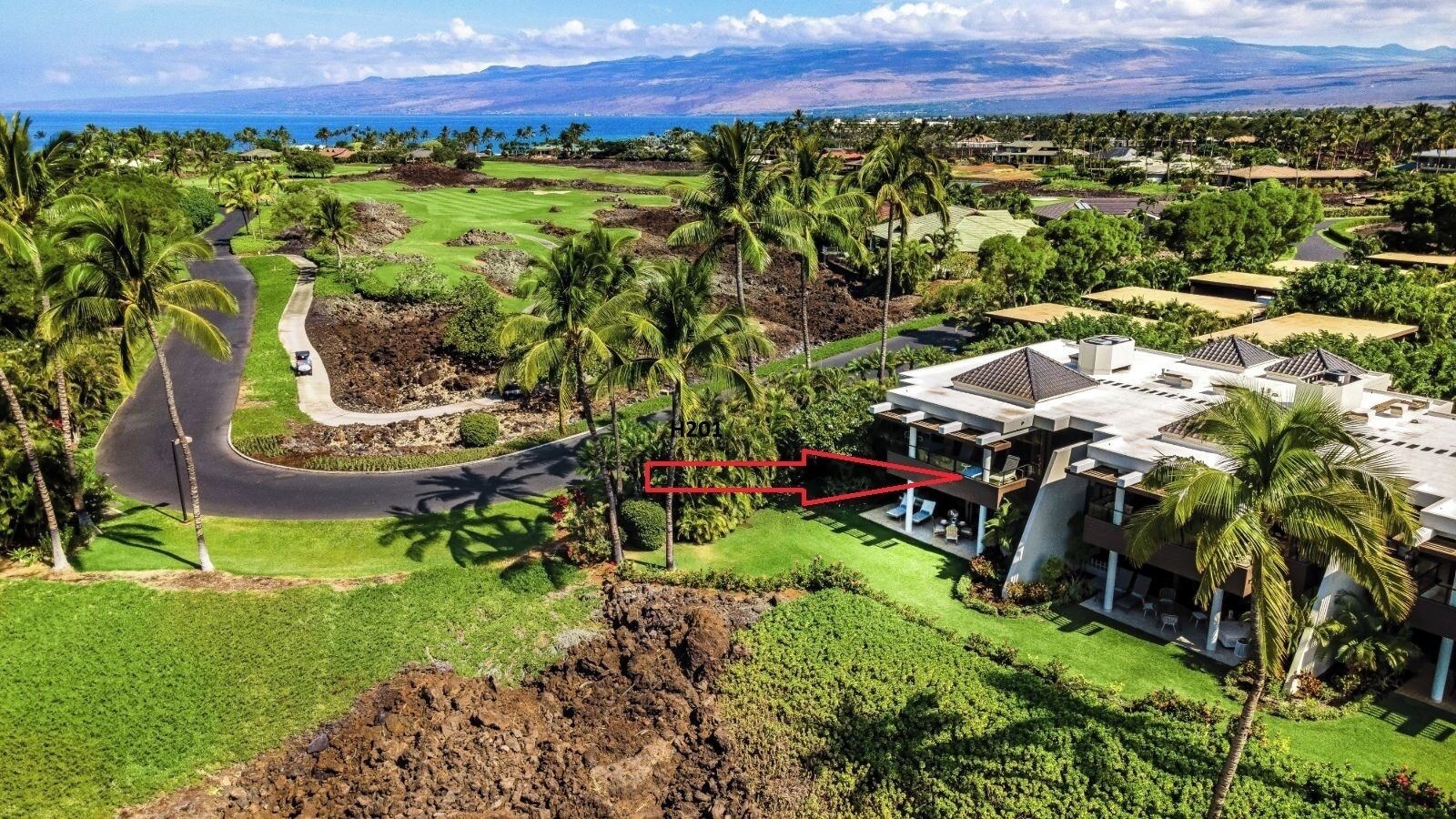 A modern hotel with a pool, surrounded by lush greenery and a golf course.