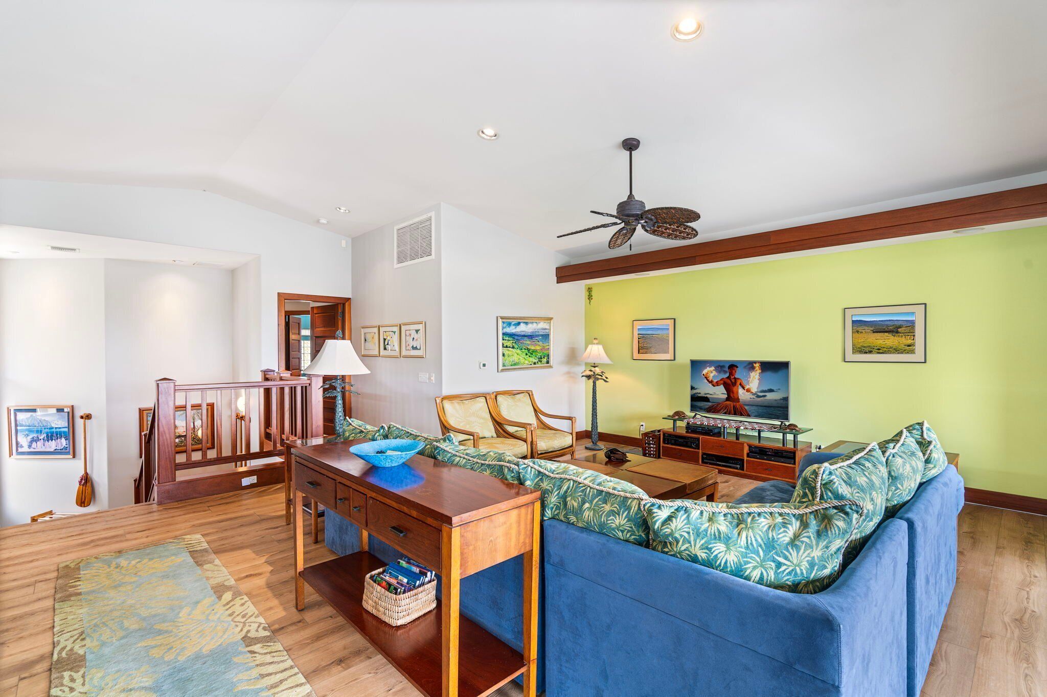 A living room with a blue sofa, wooden coffee table, and a ceiling fan.