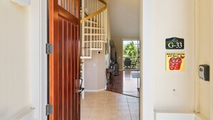 A hallway with a wooden door, a staircase, and a sign indicating room G-33. - 2 Bdrm Plus Loft - AC & Wifi - Concierge Included - Lanai!! - Vrkcv (Waikoloa)