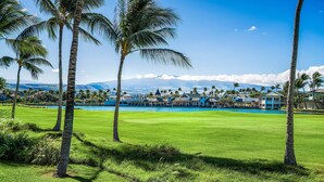 A golf course with a pool, palm trees, and a view of a mountain range. - 2 Bdrm Plus Loft - AC & Wifi - Concierge Included - Lanai!! - Vrkcv (Waikoloa)