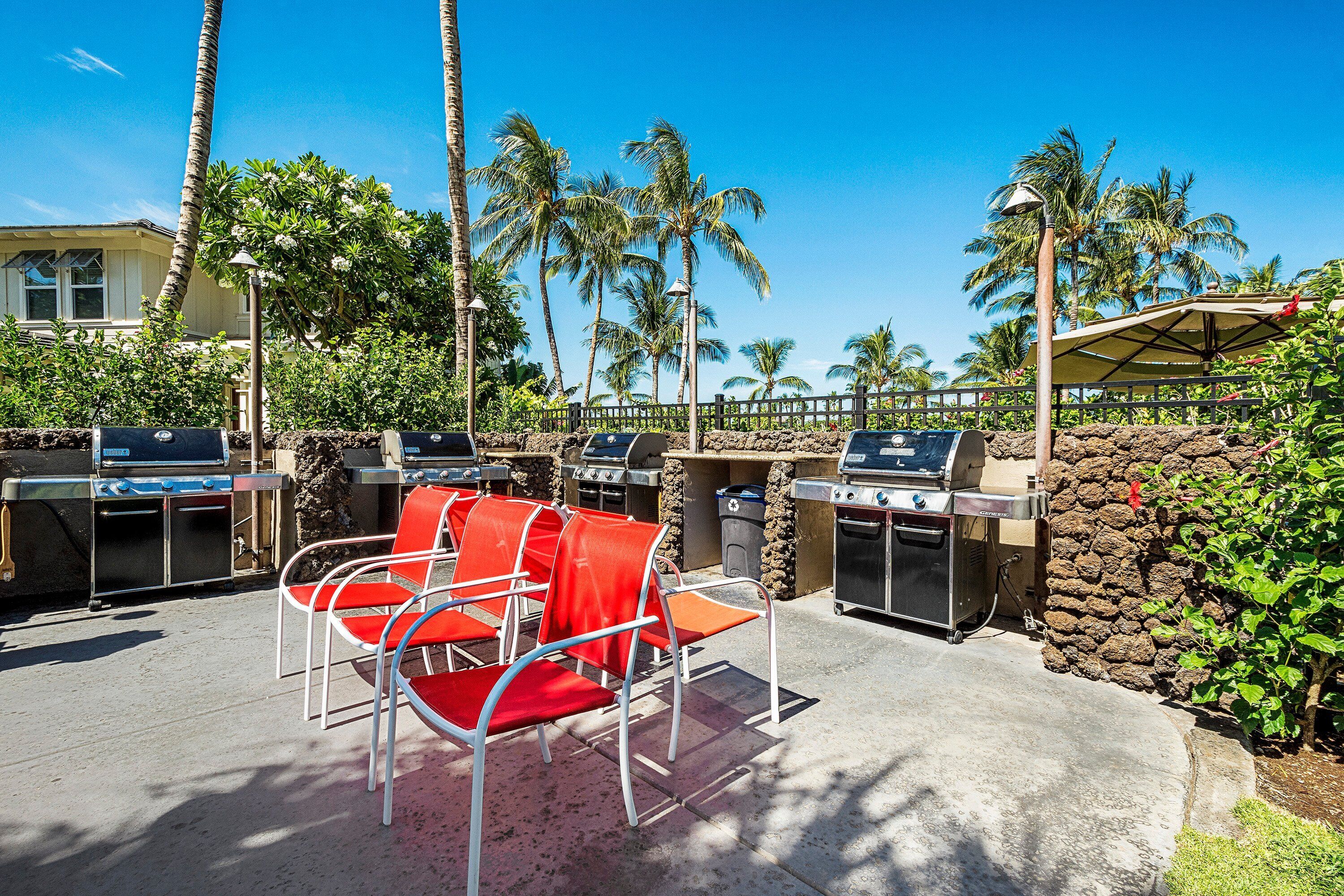 An outdoor seating area with red chairs and a barbecue station.