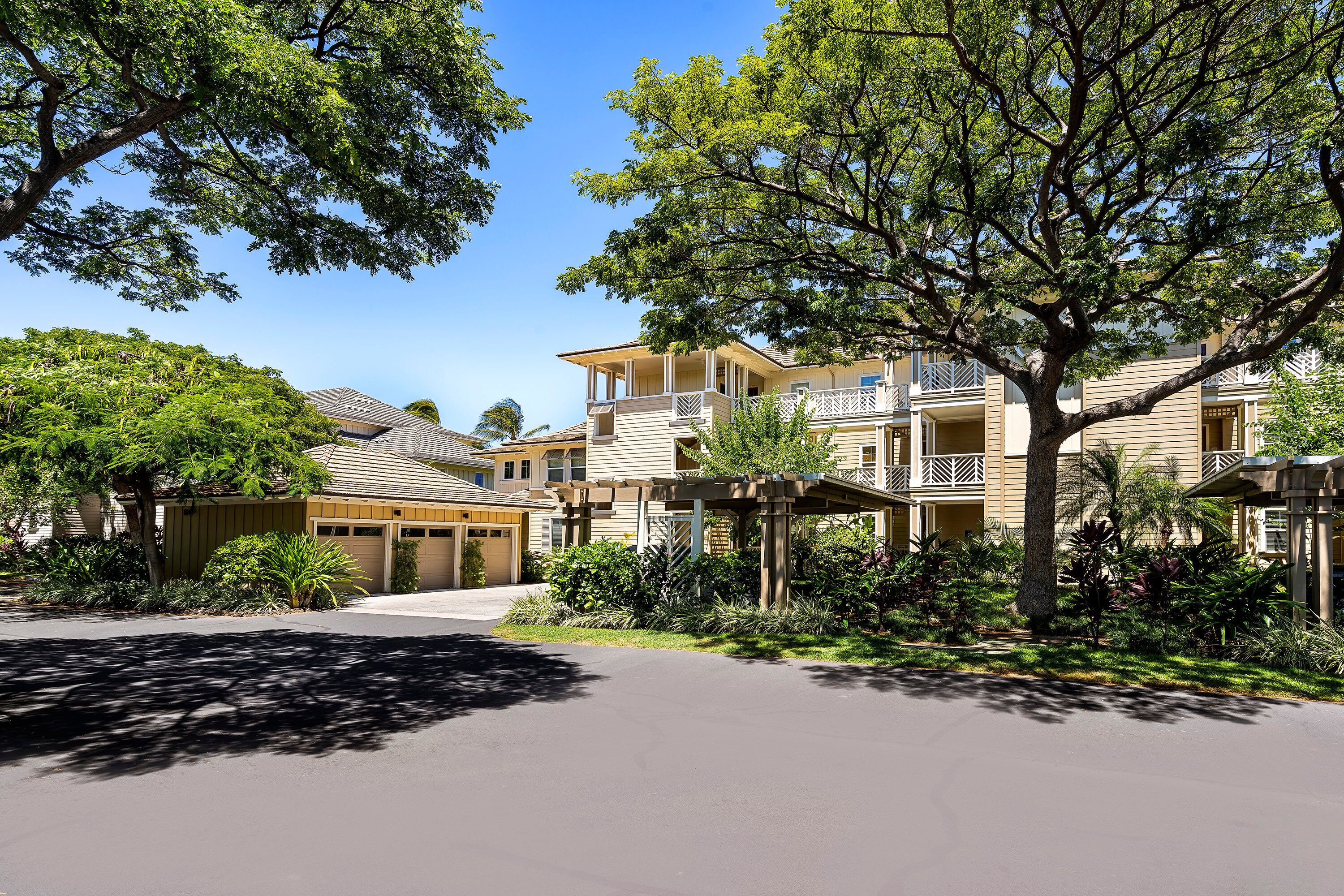 A residential area with multiple two-story houses, a paved driveway, and lush greenery.