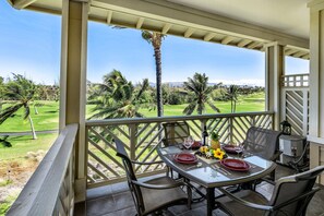 A covered outdoor dining area with a table set for two, overlooking a golf course. - 2 Bdrm Plus Loft - AC & Wifi - Concierge Included - Lanai!! - Vrkcv (Waikoloa)