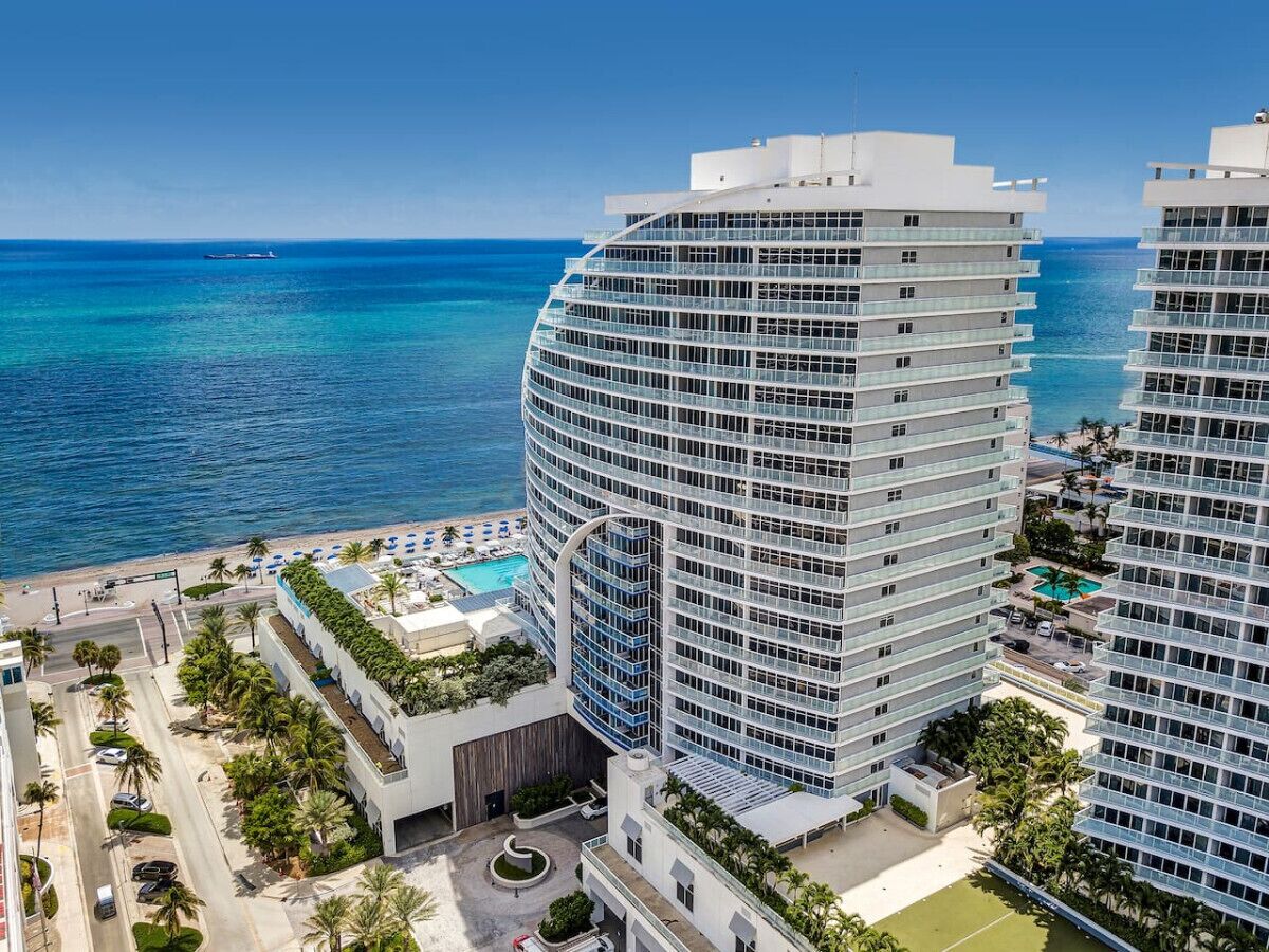 Un hotel moderno con facciata curvilinea, piscina sul tetto e vista sull'oceano.