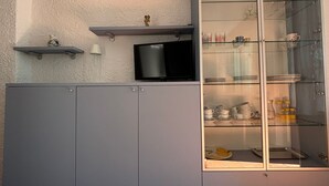 A kitchen with grey cabinets, a microwave, and a glass display cabinet with dishes. - Quiet apartment in front of Corsica (Colle D'orano)