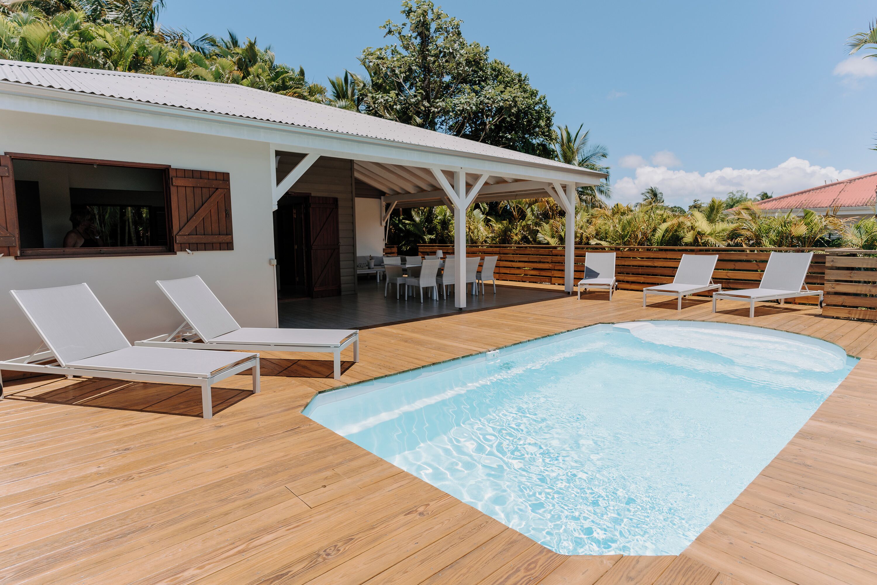 A poolside area with lounge chairs and a covered patio.
