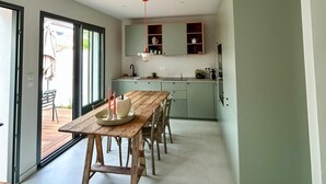 A modern kitchen with a wooden dining table and chairs, a built-in oven, and a large window. - Charming 2-bedroom house in La Flotte-en-Ré, near beach and port (La Flotte)