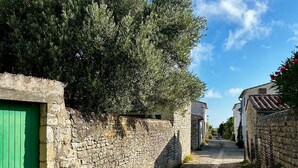 A narrow cobblestone street flanked by stone walls and green shutters, leading to a building with a tiled roof. - Charming 2-bedroom house in La Flotte-en-Ré, near beach and port (La Flotte)