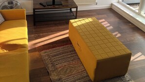 Una sala de estar con sofá, reposapiés y mueble para televisión.