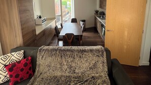 Un espacio habitable compacto con sofá, mesa de comedor y zona de cocina.