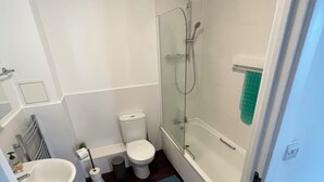 Un baño con lavamanos, inodoro y bañera blancos.