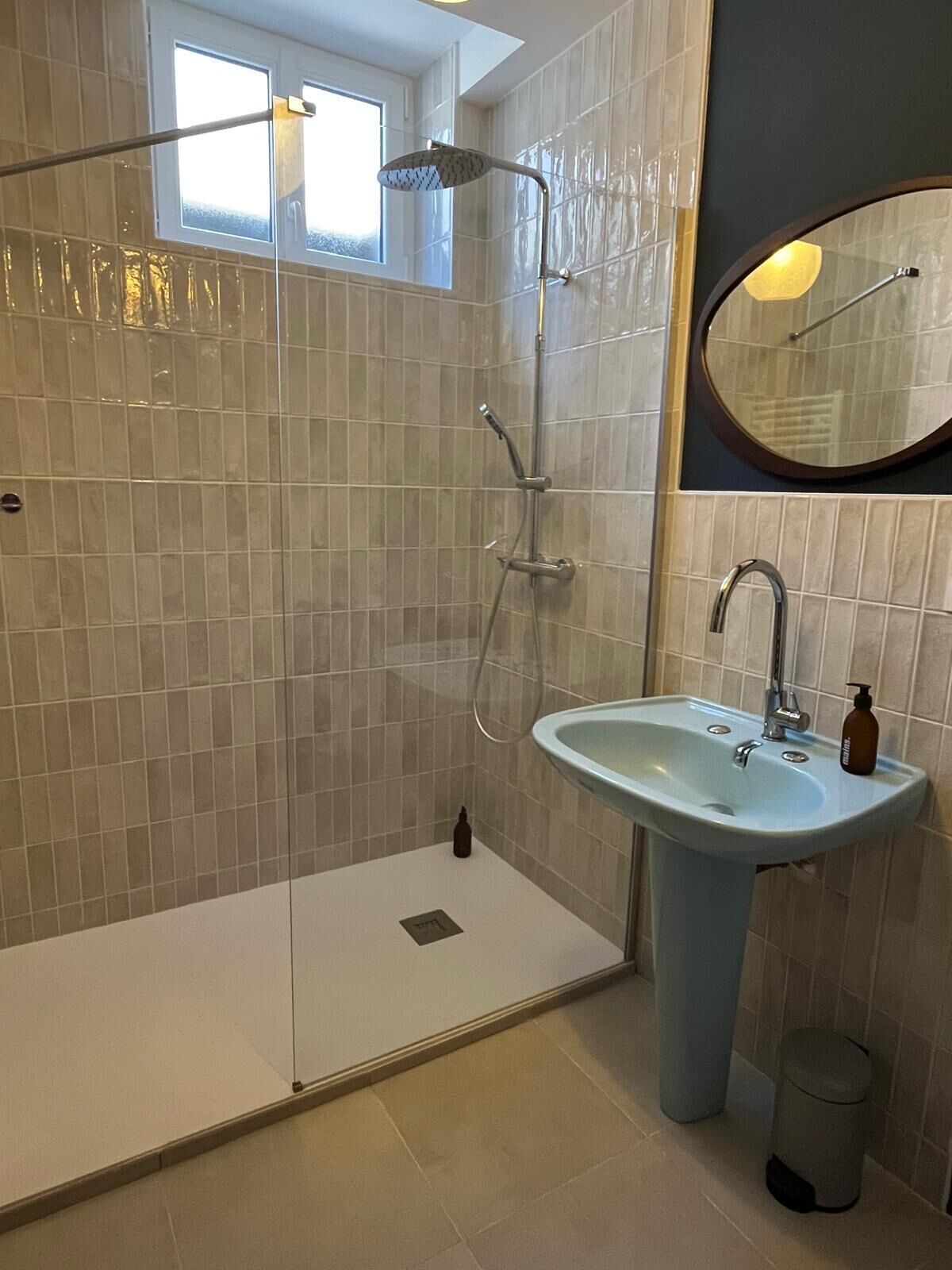 A bathroom with a glass-enclosed shower, a sink, and a mirror.