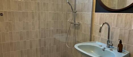 A bathroom with a glass-enclosed shower, a sink, and a mirror.