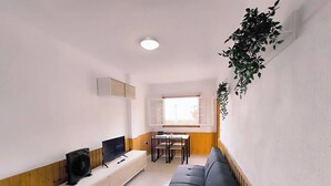 Un espace de vie compact comprenant un canapé, un téléviseur et une table à manger.