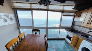 A kitchen with a large dining table, a washing machine, and a view of the sea. - Atlantic Dream Sunset (Mesa del Mar)