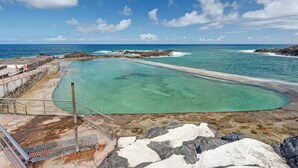A clear, turquoise pool surrounded by rocky terrain and the ocean. - Atlantic Dream Sunset (Mesa del Mar)
