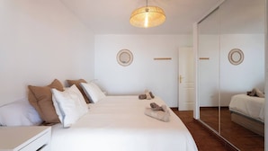 Une chambre d’hôtel avec un grand lit, une table de chevet, un miroir et un luminaire au plafond.