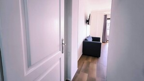 Un pasillo con un sofá de color oscuro y una puerta blanca.