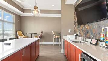 A modern kitchen with a large island, red cabinets, and a flat-screen TV mounted above the island.