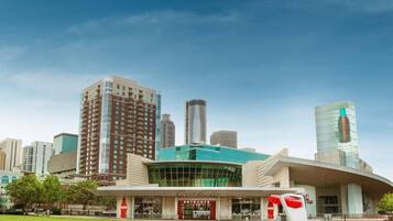 A modern building with a glass facade and a Coca-Cola logo, surrounded by a well-maintained lawn and other high-rise buildings in the background.