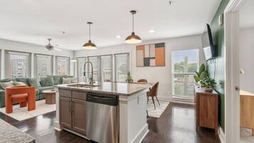 A modern kitchen with a central island, built-in dishwasher, and pendant lighting.