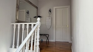 Een trap met witte balustrades en houten treden, leidend naar een kamer met een witte deur en een plafondlamp.