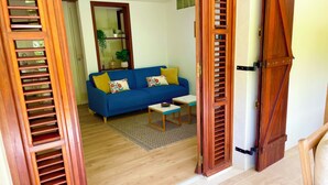 Un soggiorno con un divano blu, un tavolino e una porta in legno a persiane.