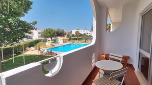 A balcony with a view of a swimming pool, a table, and chairs. - Comfortable apartment in a hotel residence, Chill and festive atmosphere (Albufeira)