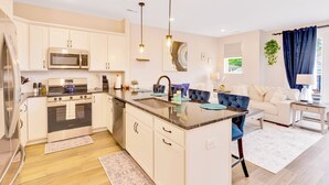 Una cocina moderna con armarios blancos, electrodomésticos de acero inoxidable y una isla central con asientos.