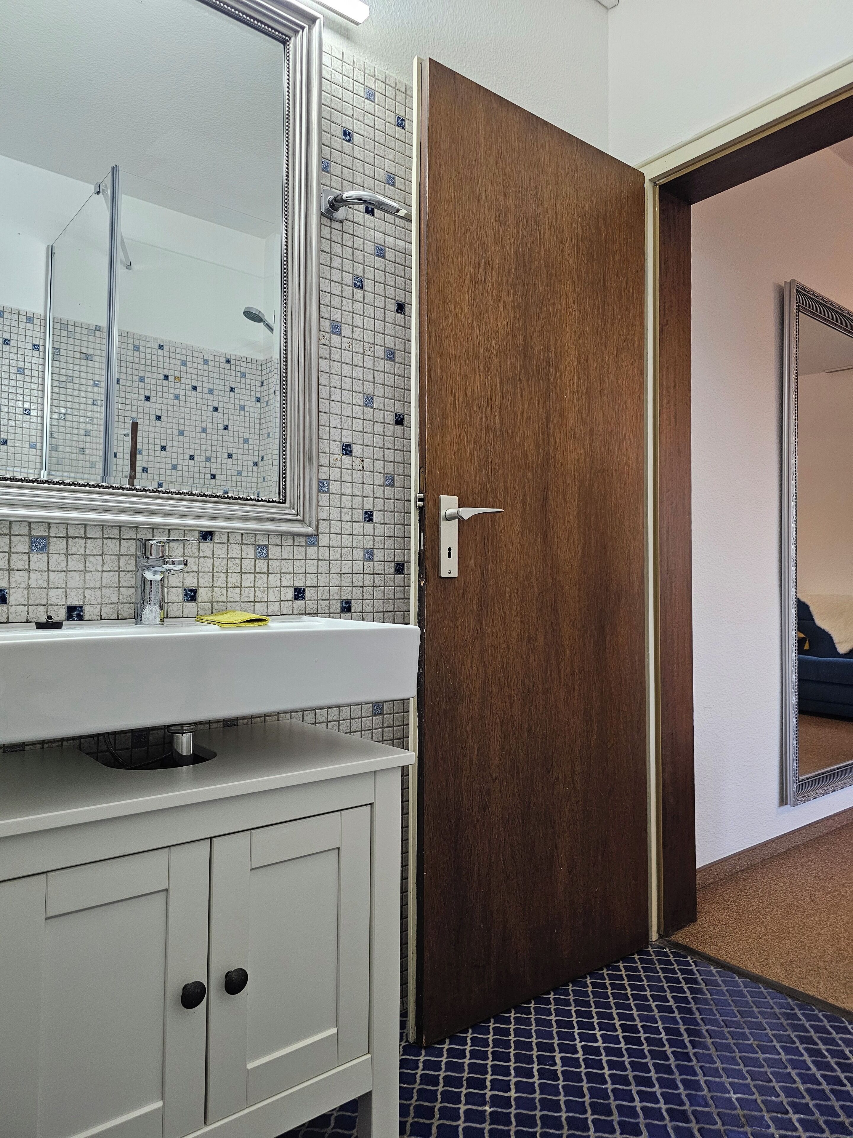 A bathroom with a white sink, a mirror, and a shower.