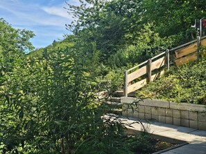 A wooden staircase leading up a hill, surrounded by dense greenery.