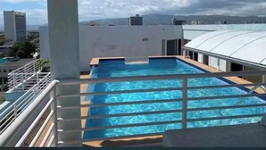 A rooftop pool with a view of the cityscape and mountains in the background.