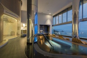 A modern indoor pool area with a glass barrier, seating, and a view of the sea. - Luxe Oceanfront Retreat on Beach, Puerto Vallarta (Puerto Vallarta)