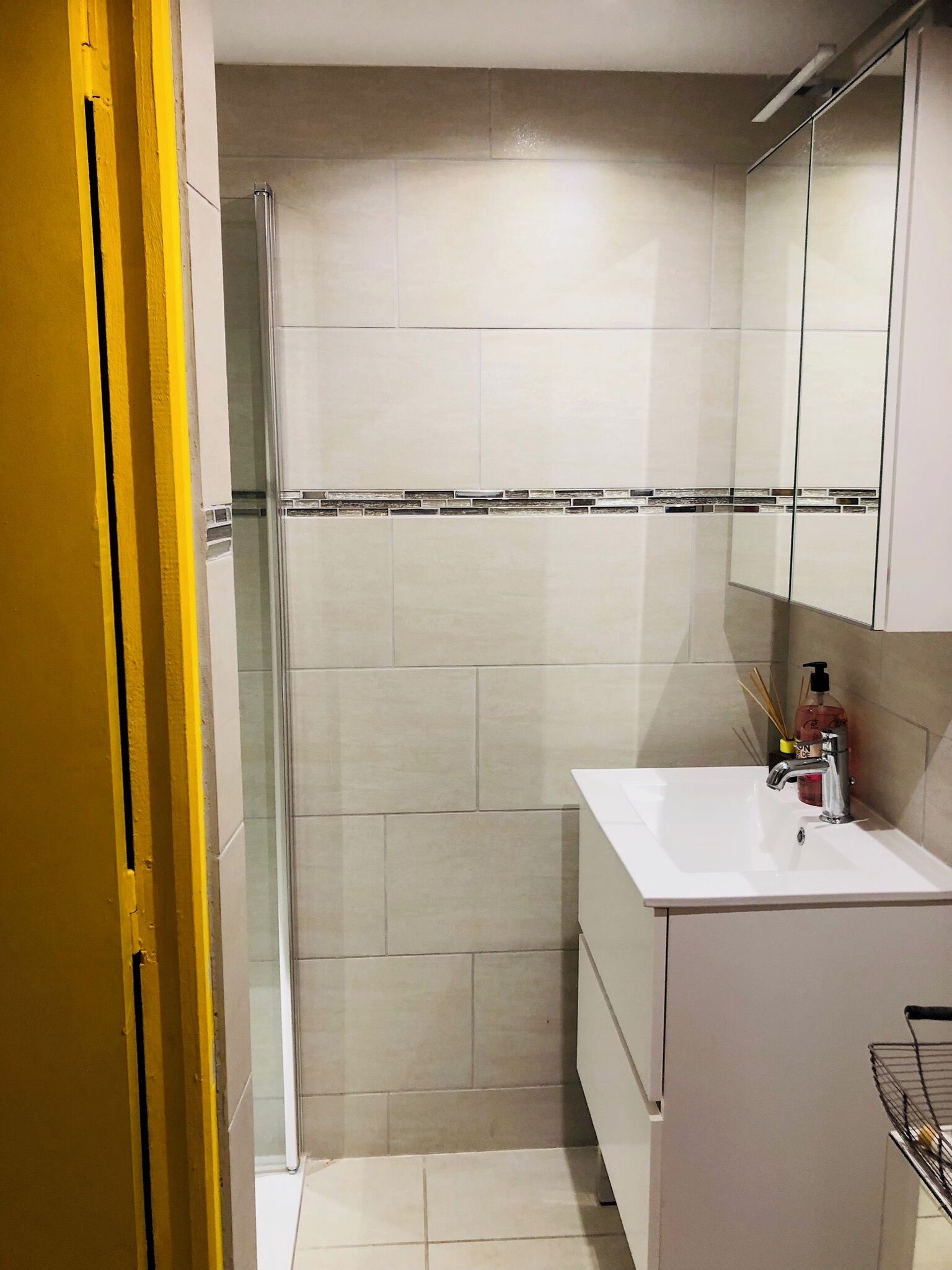 A bathroom with a shower, a sink, and a mirror.