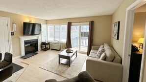 Una sala de estar con chimenea, televisor, sofá y una mesita de centro.