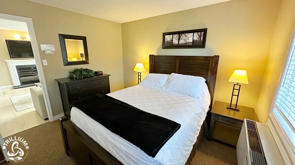 A hotel room with a bed, bedside lamps, a nightstand, a dresser, a mirror, and a window with blinds. - Blue Mtn 1 Bedroom with Mountain View (The Blue Mountains)