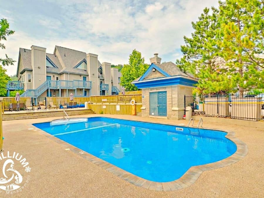 A swimming pool surrounded by a building with multiple balconies and a small structure with a blue roof.