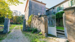 A courtyard with a stone wall, a metal gate, and buildings with tiled roofs.