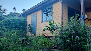 A single-story house with a beige exterior, a window with a curtain, and a door. - Fare atihau vairao  (Taiarapu-Ouest)