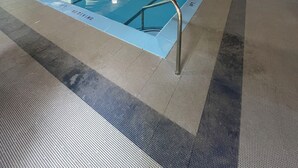 Sisätiloissa sijaitseva uima-allas, jossa on selkeät kaistamerkinnät, hyppytorni ja pelastajan valvomopaikka.