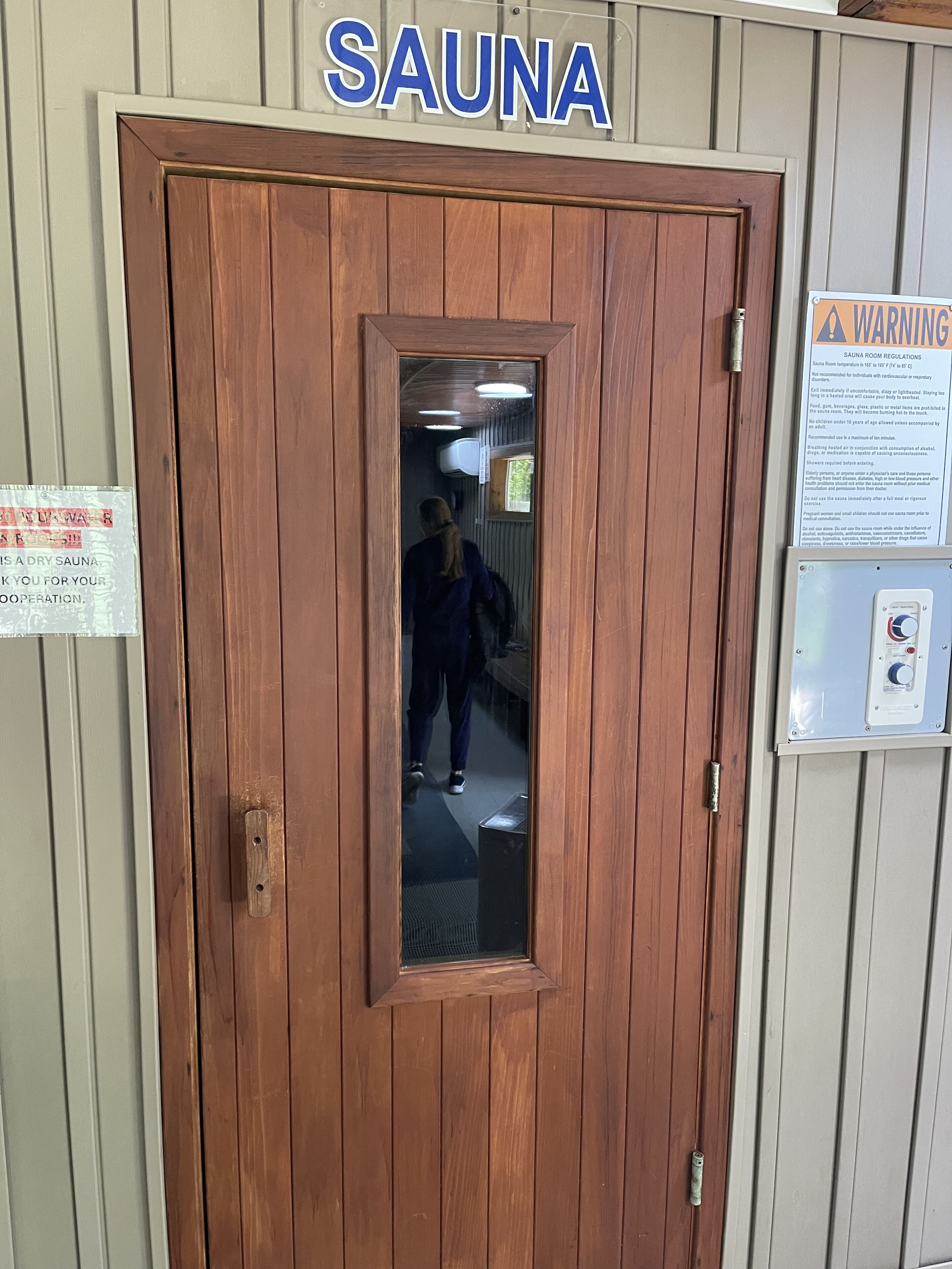 Une porte en bois avec une pancarte au-dessus indiquant « SAUNA ».